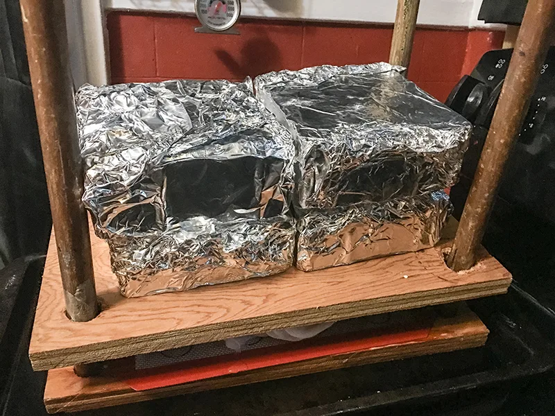 The cheese press with 20 pounds of weight on top of it and the cheese inside it.