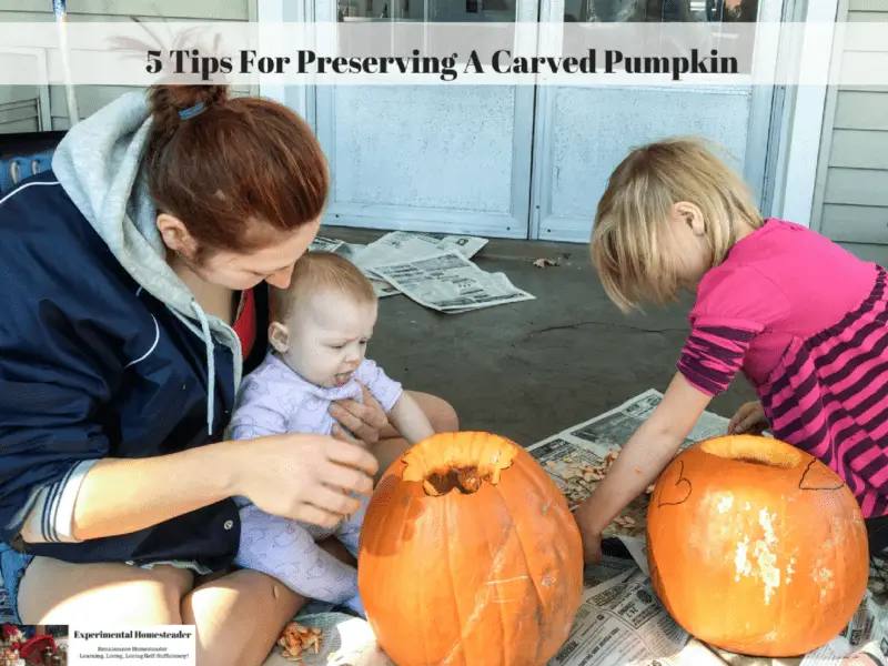 A mother and her daughters carving a pumpkin.
