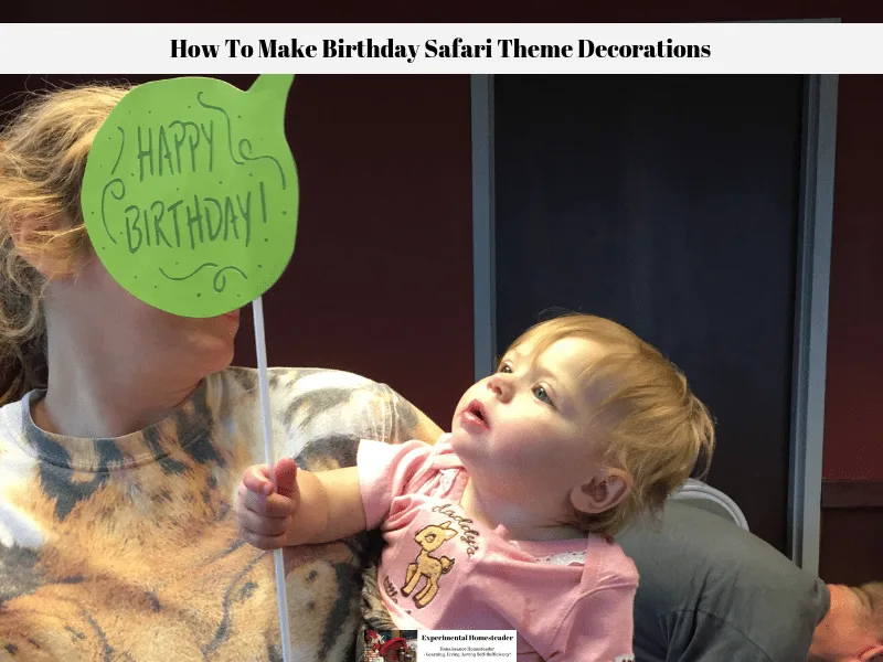 Alivia holding one of the birthday safari theme party photo prop signs.