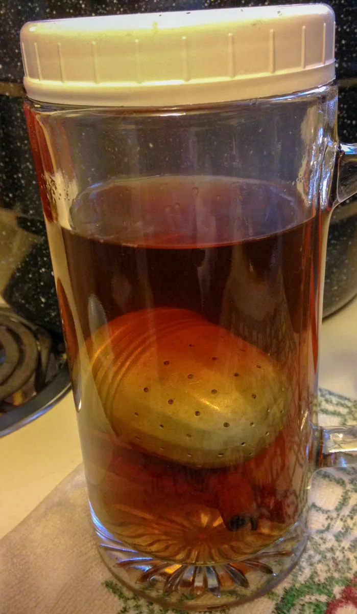 The tea ball and cinnamon sticks in a. glass container.