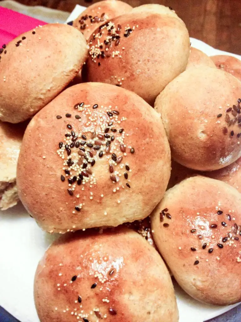 Homemade Swerve Dinner Rolls topped with grains and seeds, on a plate ready to eat.