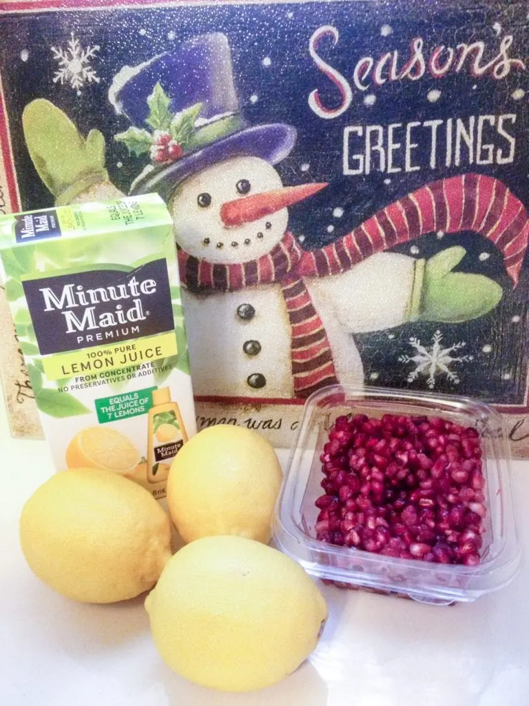 Minute Maid Lemon Juice, fresh lemons and pomegranate fruit on a countertop waiting to be made into this easy pomegranate lemonade drink recipe.