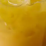Ice in a glass filled with saffron infused orange juice.