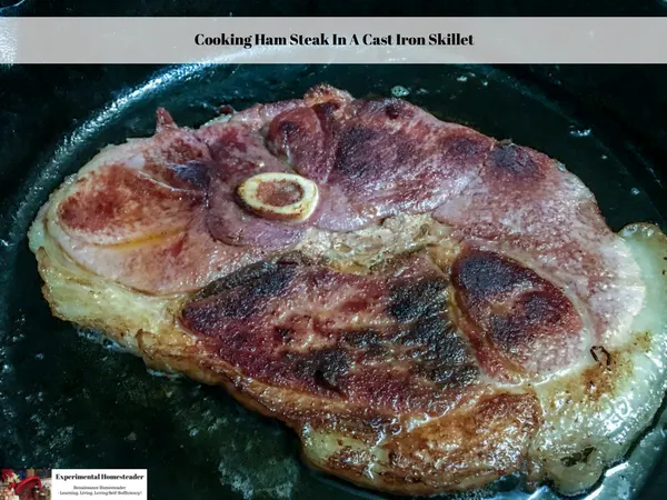 A ham steak cooking in a cast iron skillet.