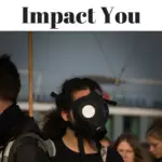 A woman in a gas mask and other people standing around her facing away from the camera.