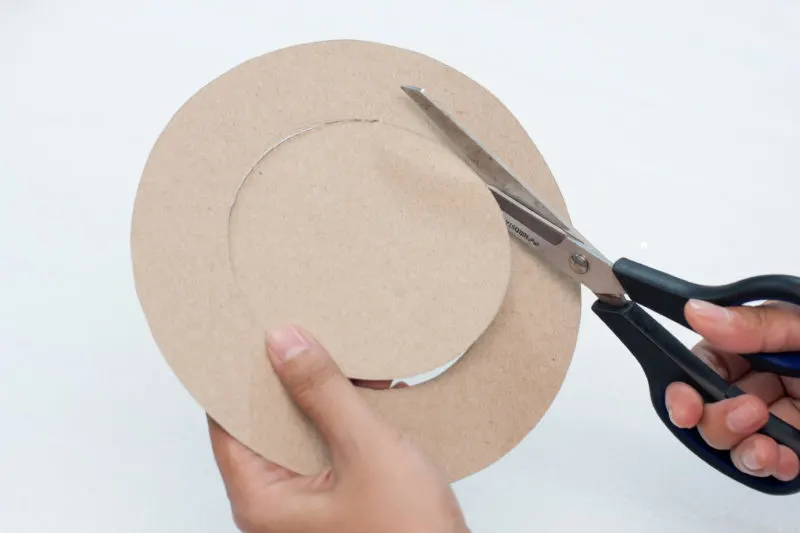 Using scissors to cut out the circles that were drawn on the cardboard.