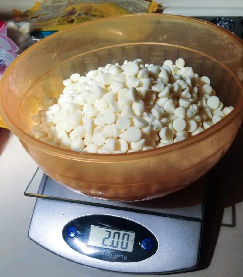 White chocolate in a bowl on top of a scale.