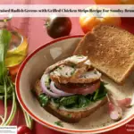 An open faced braised radish greens with grilled chicken sandwich on a plate surrounded by olive oil, whole ripe tomatoes and radishes with the tops intact.