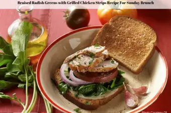 An open faced braised radish greens with grilled chicken sandwich on a plate surrounded by olive oil, whole ripe tomatoes and radishes with the tops intact.