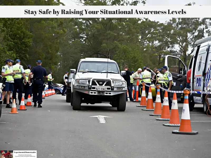 Vehicles driving down a street bordered by police offers on either side.