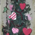 An evergreen tree decorated with heart shaped ornaments and red beads.