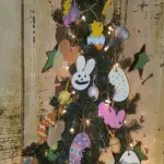 A primitive Easter tree decorated with handmade salt dough ornaments. In this photo you see a purple burlap streamer, a pink salt dough bunny rabbit head and a fake Easter egg.