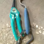 A pair of goat hoof trimmers and a hoof pick laying side by side on a table.