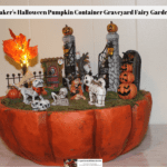 A Maker's Halloween Pumpkin Container decorated to look like a graveyard fairy garden complete with skeletons, skull animals and an LED lighted tree.