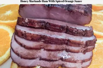 A pre-sliced Frick's Gourmet Ham With Natural Juices glazed with an orange honey sauce and sitting on a platter of orange slices.