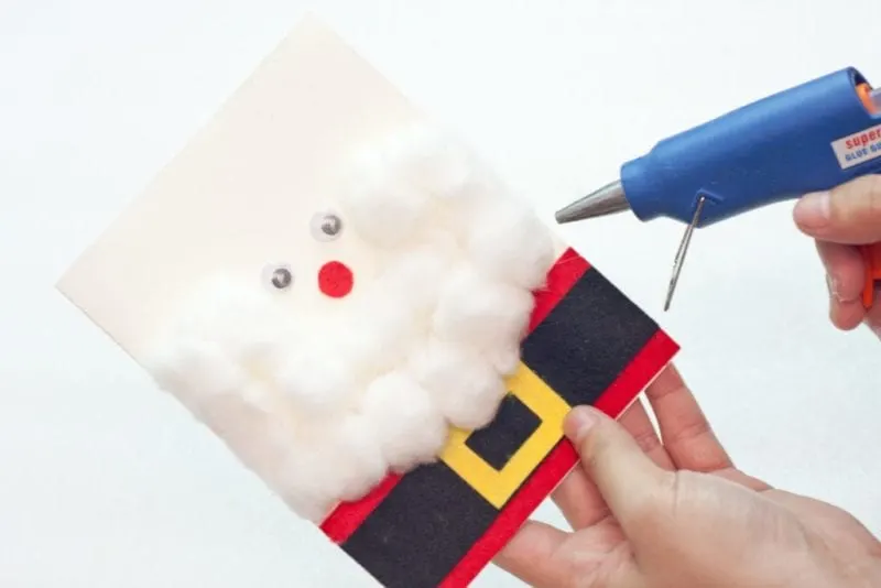 The cotton balls being glued to the side of the cute handmade card.