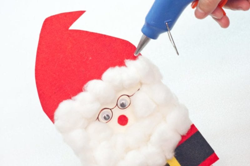 Cotton balls being glued on the cute handmade card to make Santa's hair.