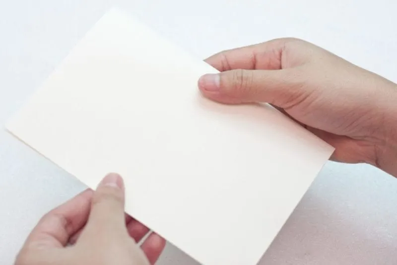 The white card stock being folded to create a greeting card.