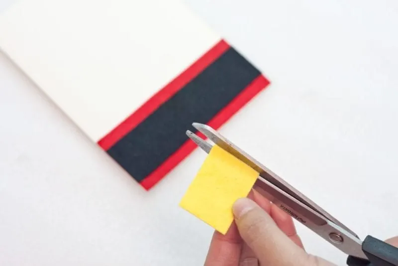 A square of yellow felt being cut.