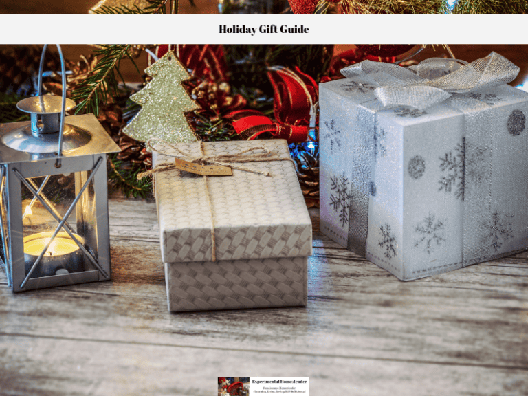A decorative metal lantern and two presents sitting in front of a Christmas tree.