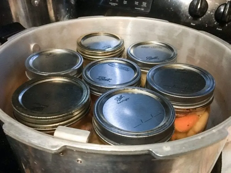 Canning jars filled with beef stew in a pressure canner.