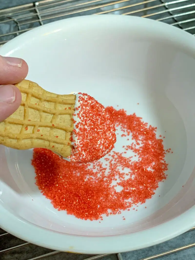 Sprinkling the white chocolate with red sprinkles to create Santa's hat.