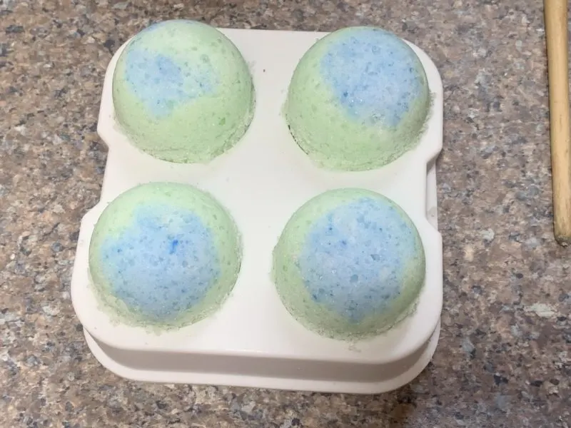 The top of the bath bombs unmolded and drying on the counter top.