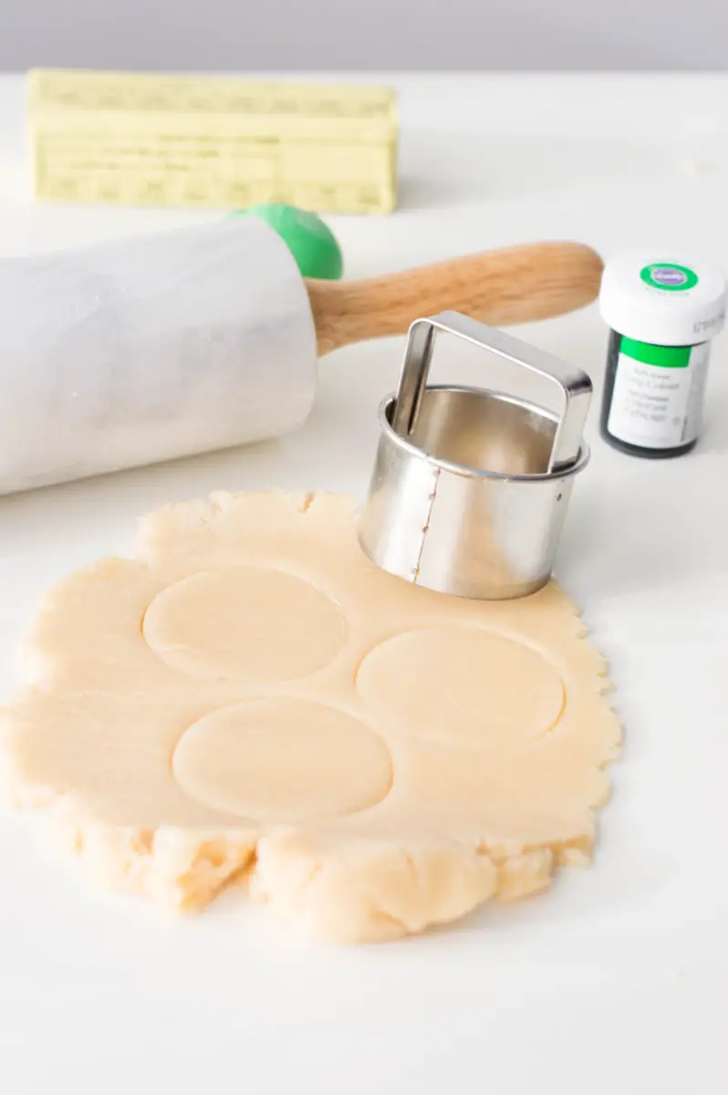 The dough being cut into circle shapes with a cookie cutter.