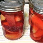 A completed red hot apple recipes canning recipe with the apples in the sealed jars.