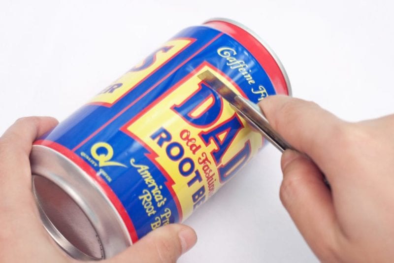 A soda can being cut with a knife.