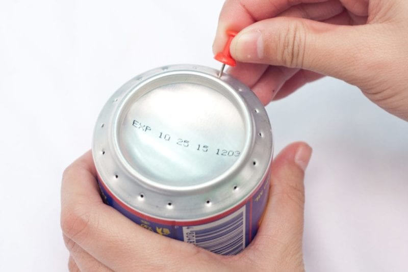Small holes being punched into the bottom of a soda can.