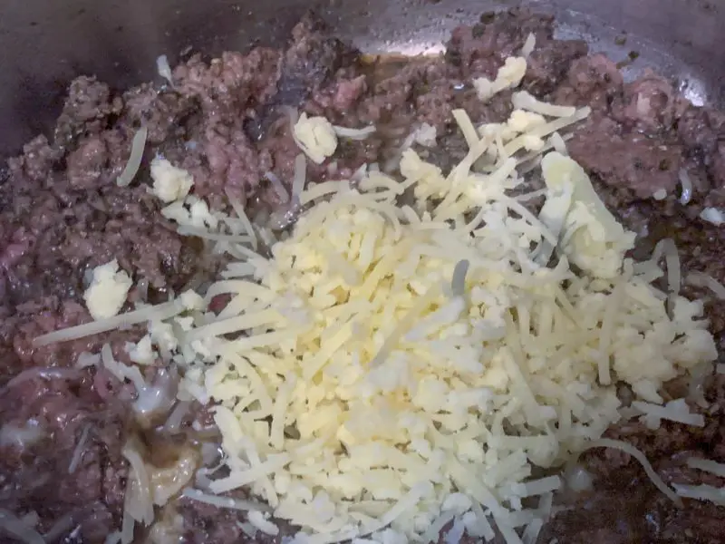 The Mahon-Menorca shredded cheese being added to the hamburger.