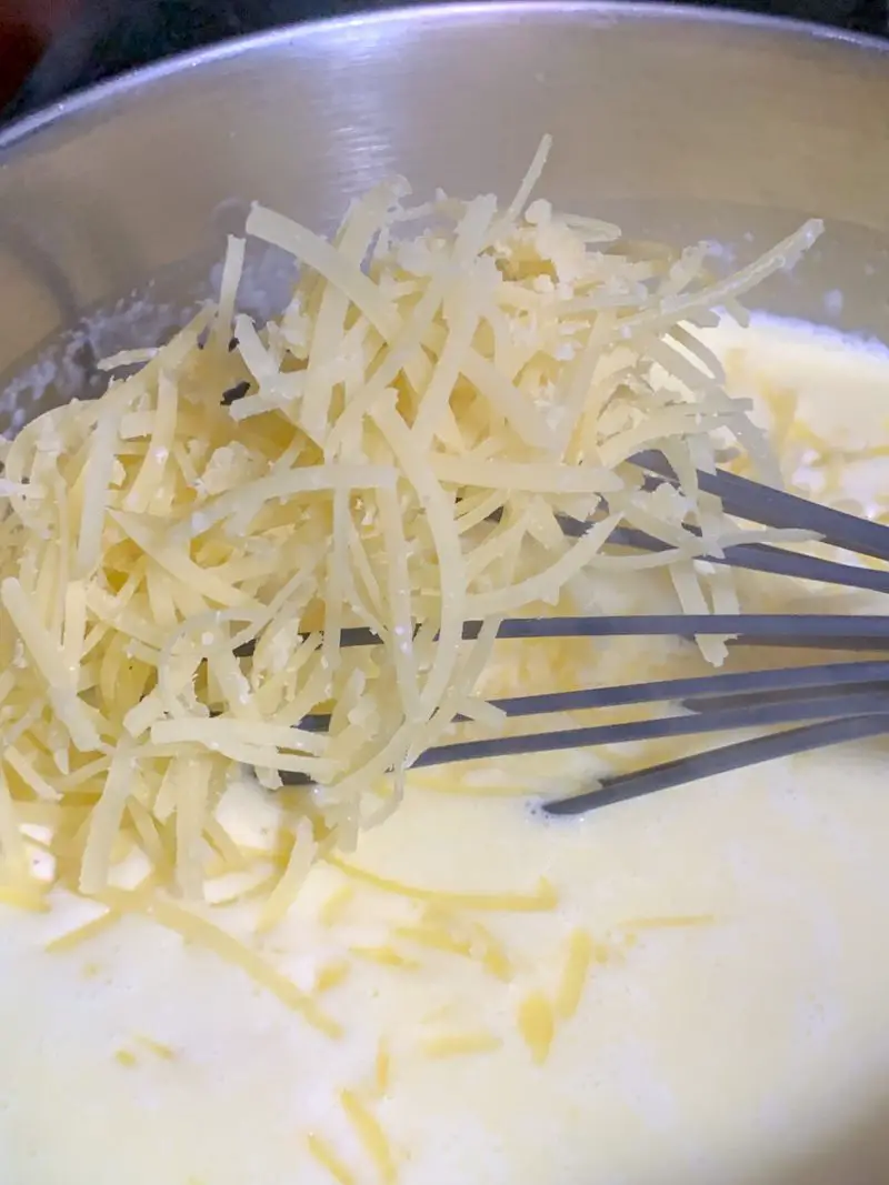 The shredded cheese being mixed into the milk mixture.