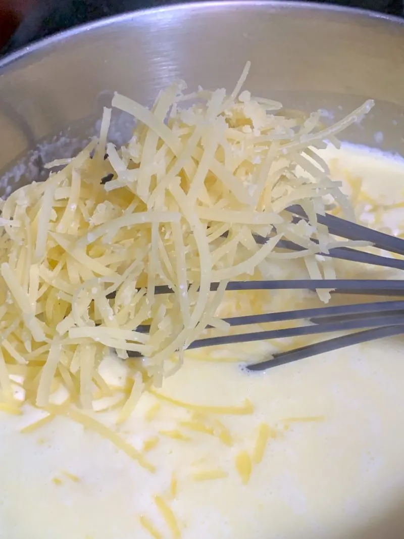 The shredded cheese being mixed into the milk mixture.