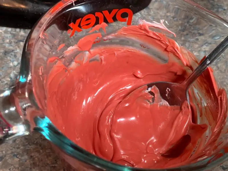 The melted candy melts in a glass measuring cup.