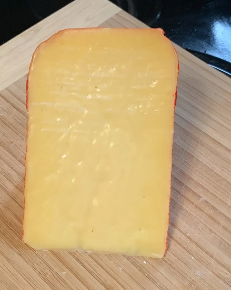The Mehon-Menorca hard cured cheese sitting on a cutting board.