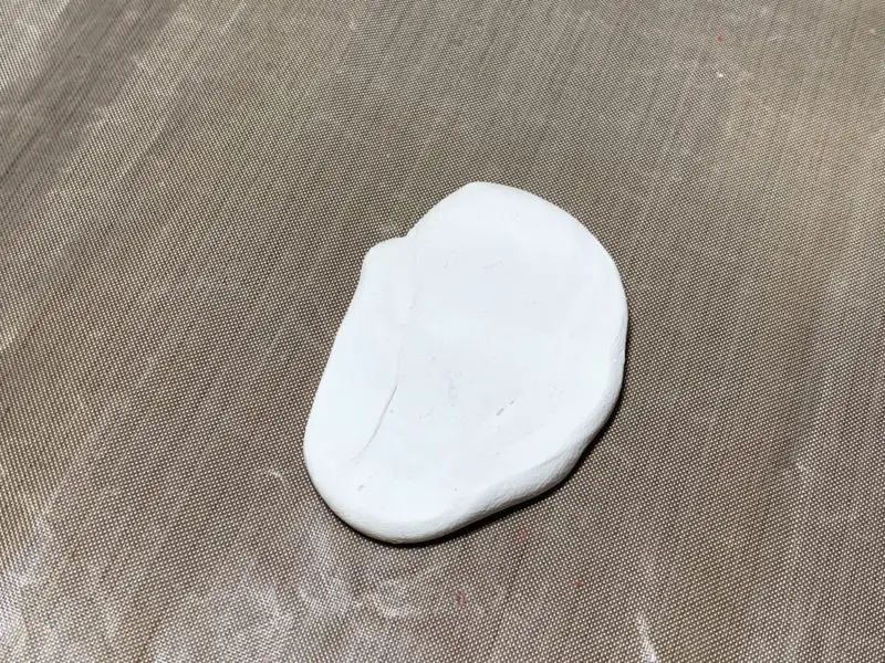 The white polymer clay rolled into a flat oval shaped piece.