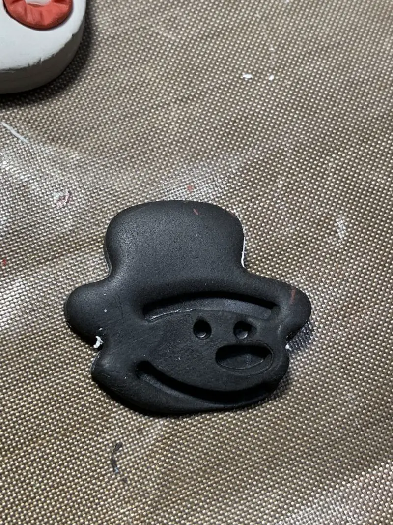 The black hat cut out of polymer clay waiting to be trimmed.