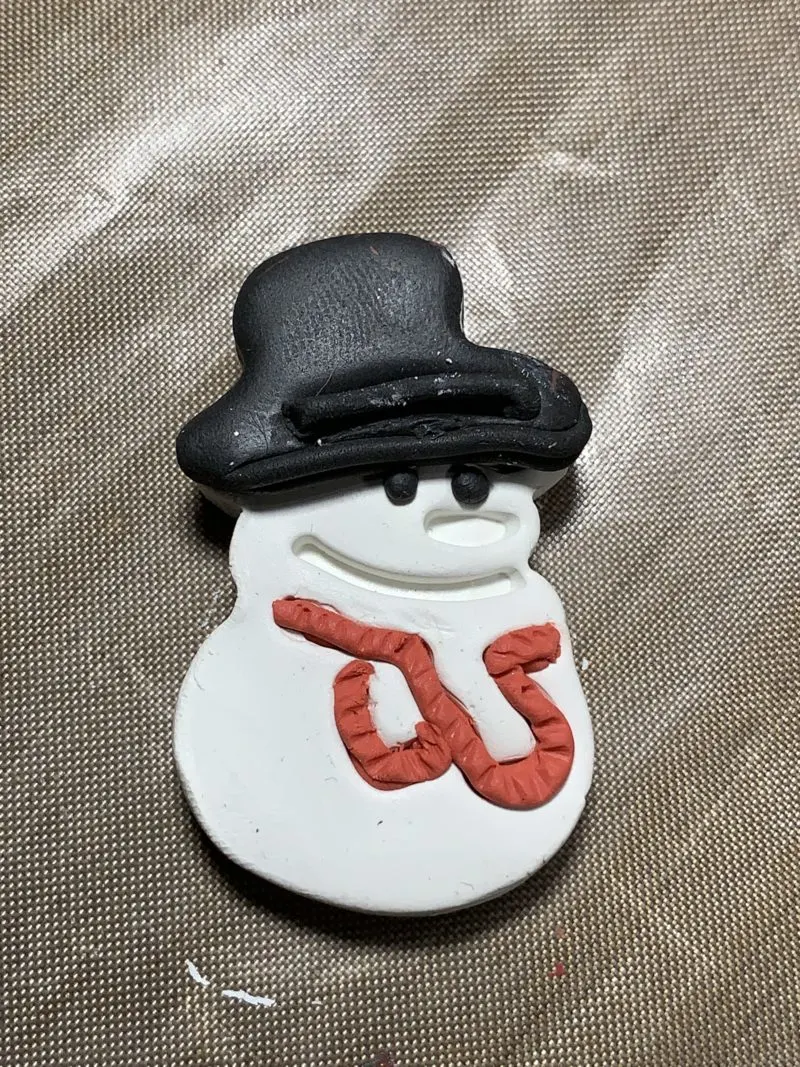 The black hat placed on top of the snowman's white hat and decorated.