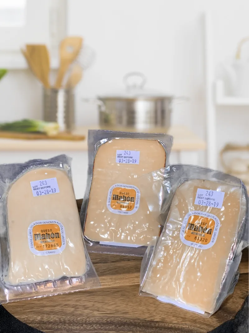 The three Mahon Cheese varieties I received sitting on a cutting board on a kitchen counter.