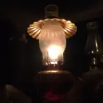 A lighted kerosene lamp sitting on a table.