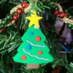A finished polymer clay Christmas ornament hanging on a Christmas tree.