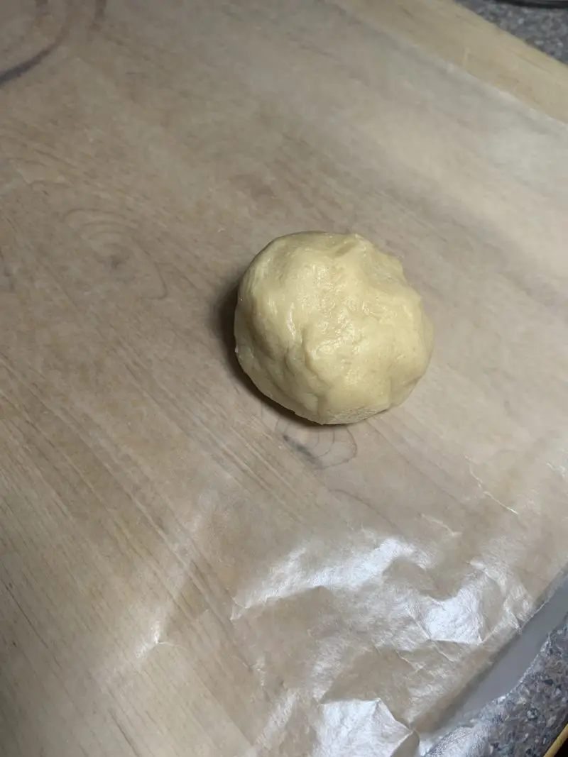 A piece of the sugar cookie dough being rolled into a ball.