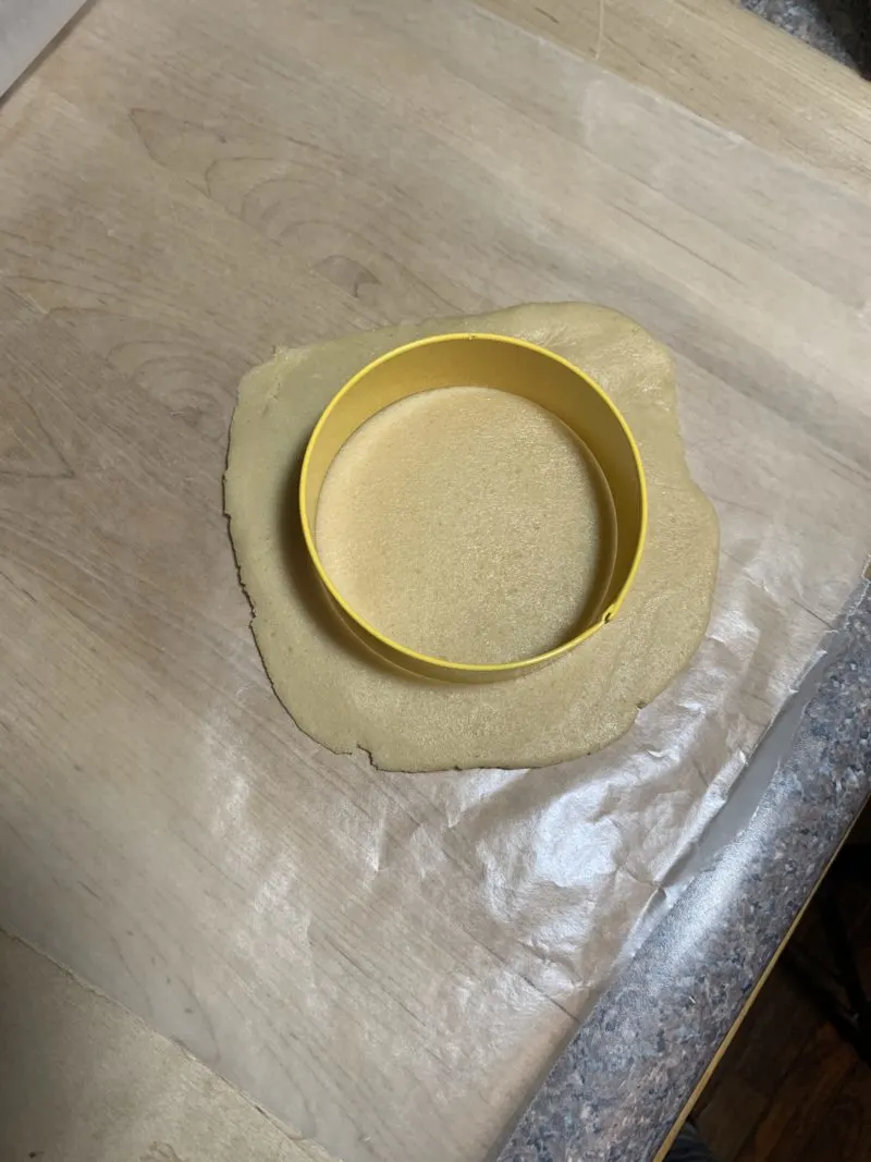 The cookie cutter on top of the sugar cookie dough.