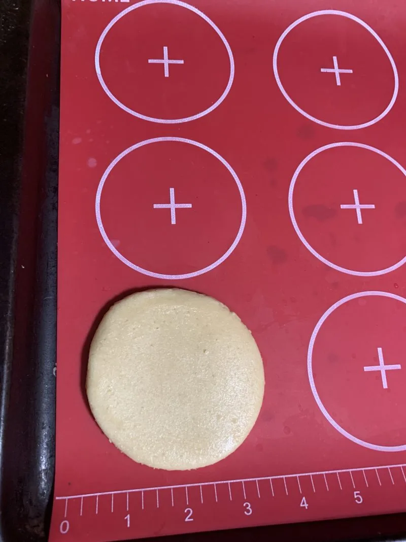 The shaped sugar cookie on a silicone mat laying on a cookie sheet.