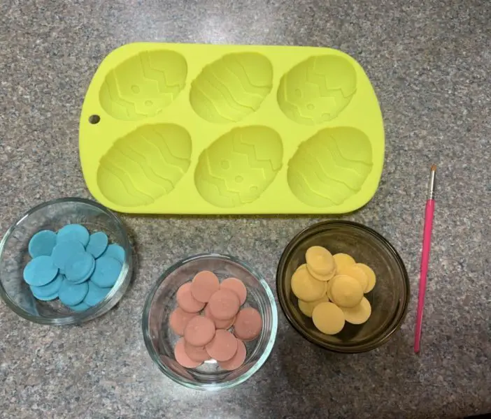 The various colored candy melts in separate glass containers.