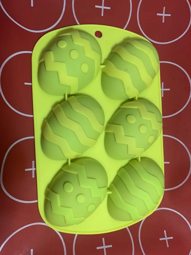 The silicone mat under the silicone mold filled with the chocolate creme filled eggs.