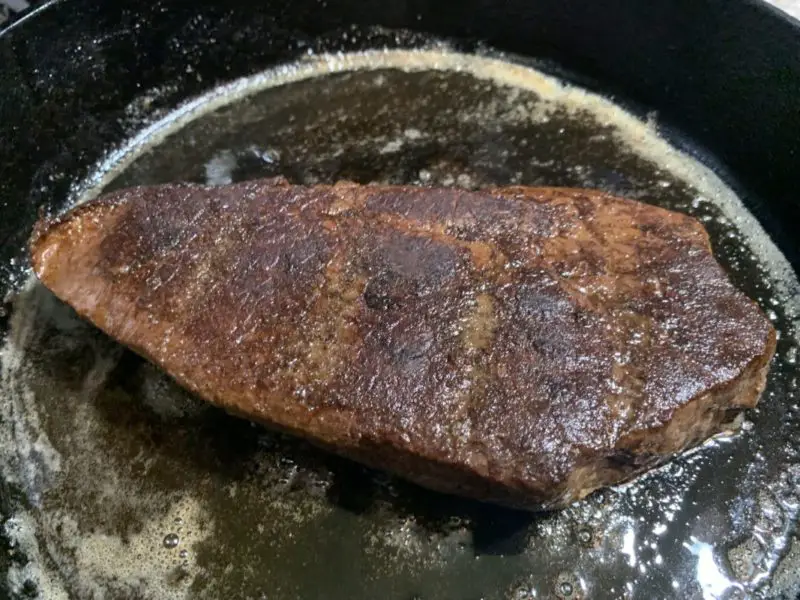 The meat in the cast iron skillet being seared.
