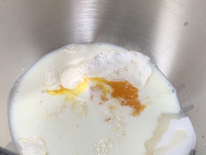 The milk, eggs, melted butter and flavoring added to the dry ingredients in the bowl.