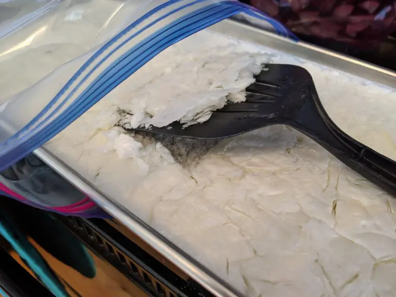 The freeze dried milk being scraped into a bag.